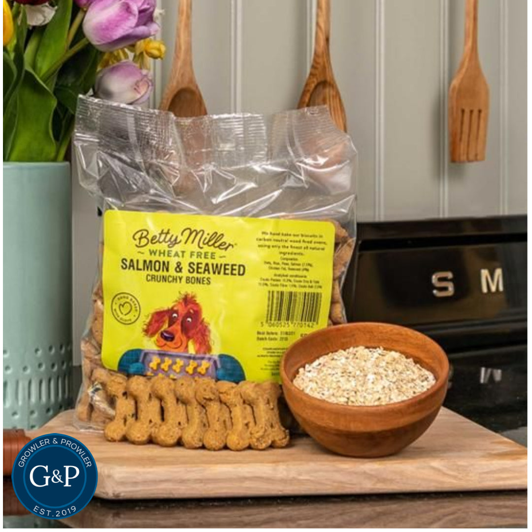 A bag of Betty Miller Salmon and Seaweed Biscuits for dogs. The biscuits are shaped like bones and have a golden brown colour.