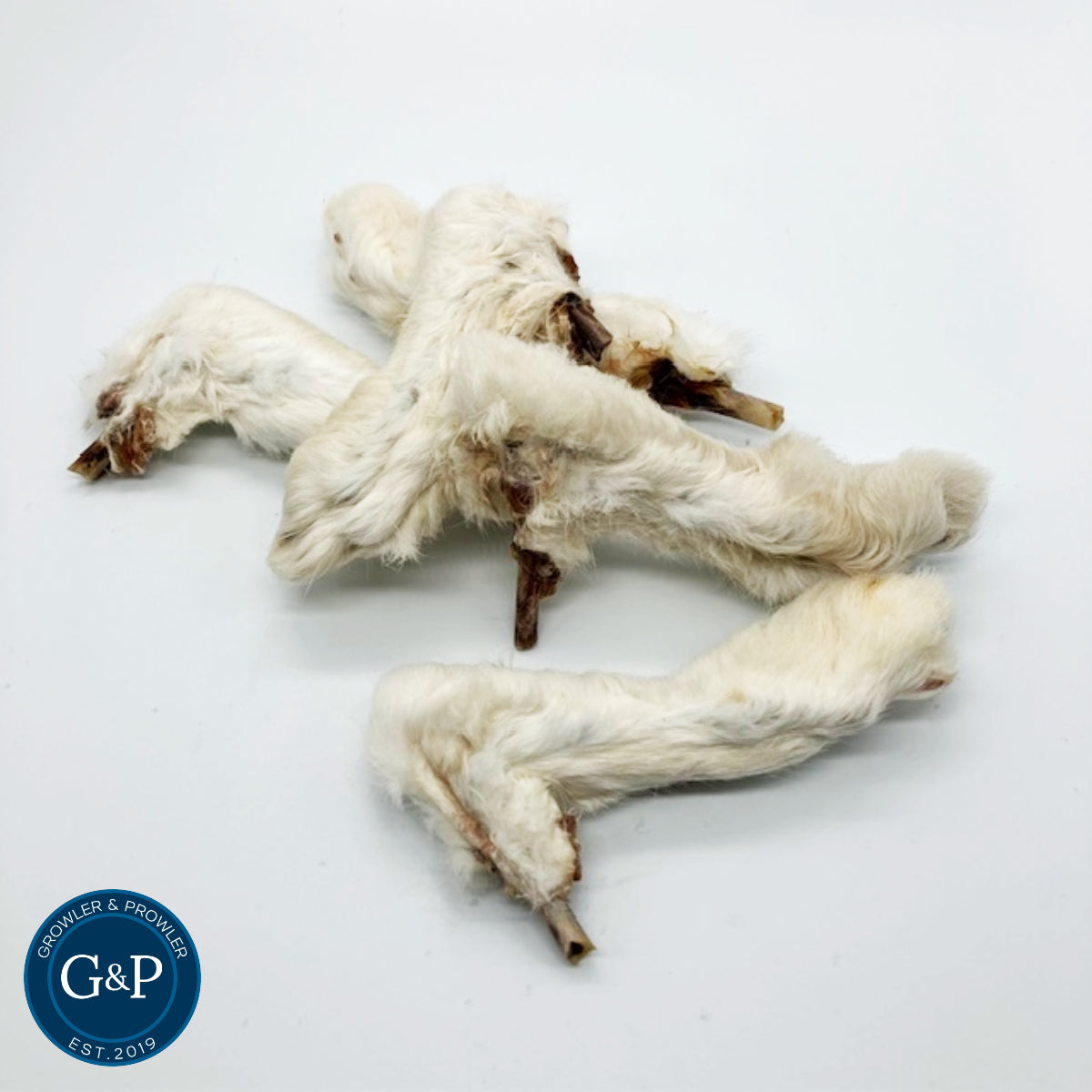 A pile of hairy rabbit feet from Growler and Prowler, a natural dog treat company based in Manchester. The feet are white and furry, with the bones still attached.